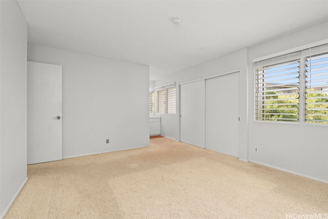 unfurnished bedroom featuring multiple windows, carpet, and a closet