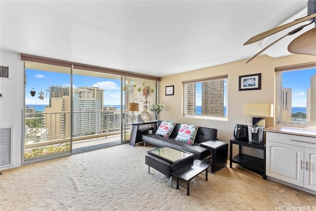 living room featuring expansive windows, visible vents, and a ceiling fan