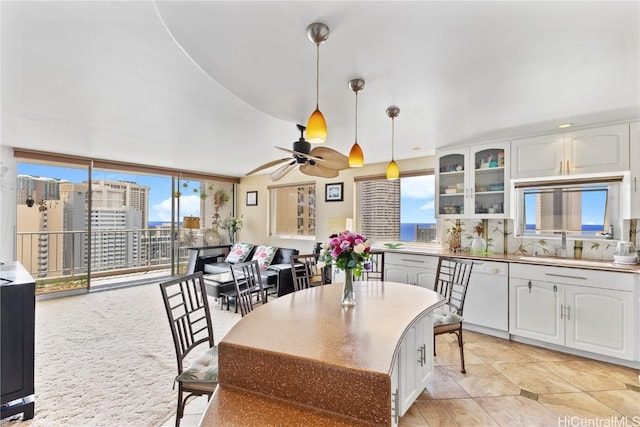 dining room featuring ceiling fan, a city view, floor to ceiling windows, and a healthy amount of sunlight