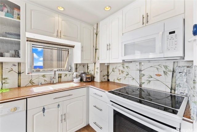 kitchen with glass insert cabinets, white appliances, white cabinets, and a sink