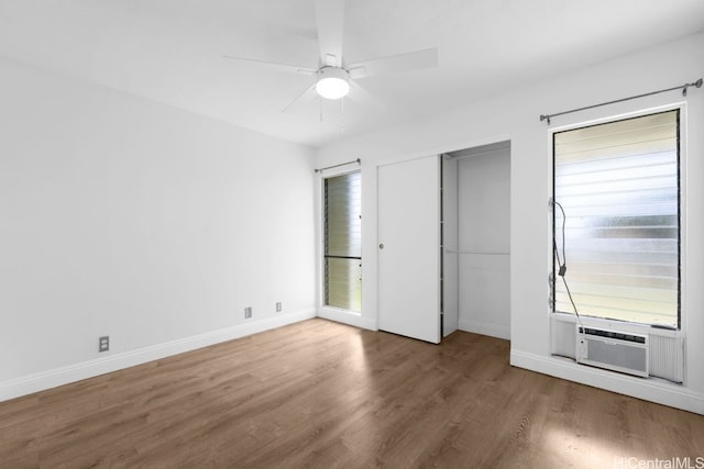 unfurnished bedroom with cooling unit, a ceiling fan, baseboards, and wood finished floors