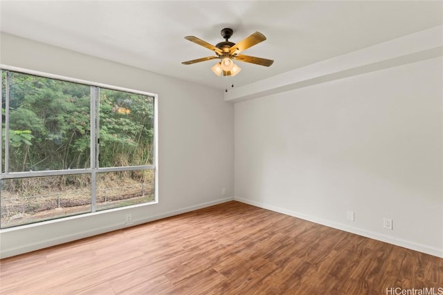 unfurnished room featuring baseboards, wood finished floors, a ceiling fan, and a healthy amount of sunlight