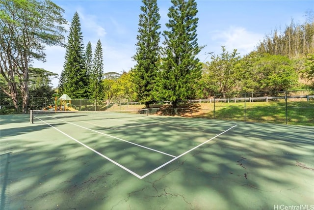 view of tennis court featuring playground community and fence