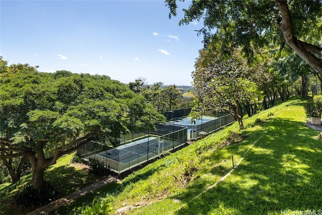 view of tennis court featuring a yard and fence