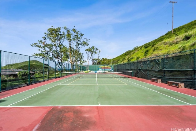 view of tennis court featuring community basketball court and fence