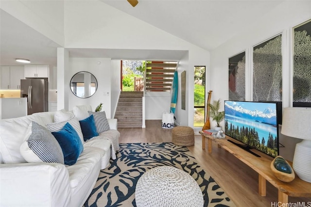 living area featuring vaulted ceiling, stairs, and wood finished floors