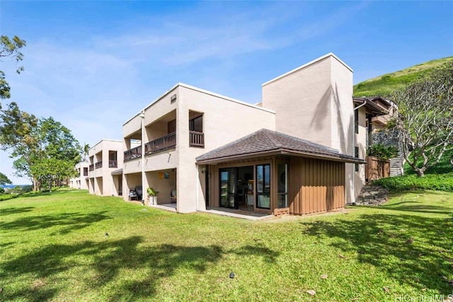 back of house with a balcony and a yard