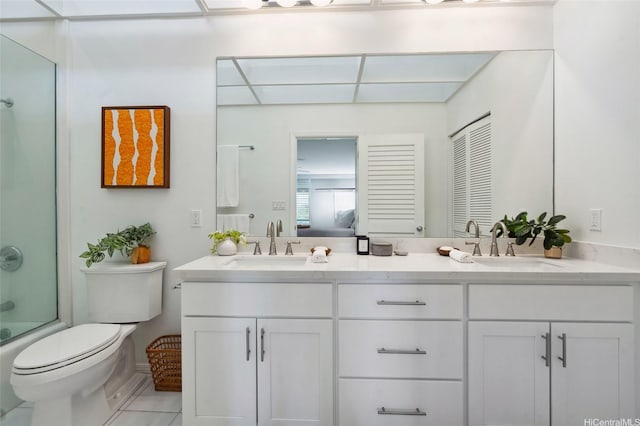 bathroom with a sink, tile patterned flooring, toilet, and double vanity