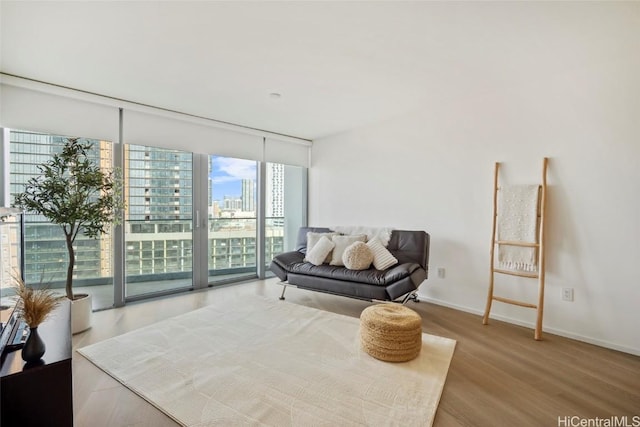 living area with a view of city, floor to ceiling windows, baseboards, and wood finished floors