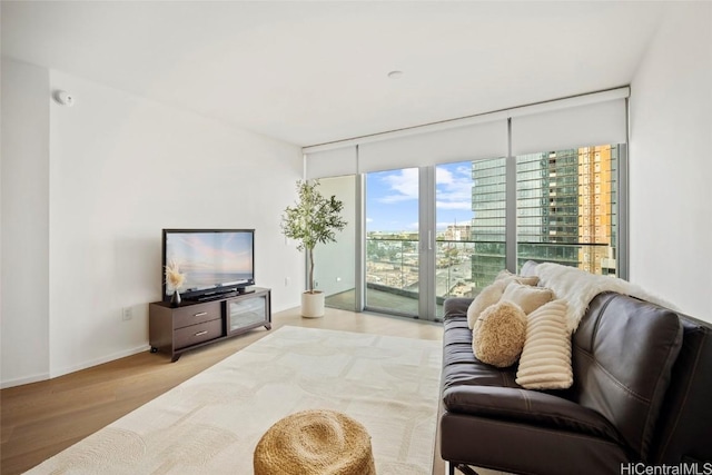 living area featuring a wall of windows, wood finished floors, and baseboards