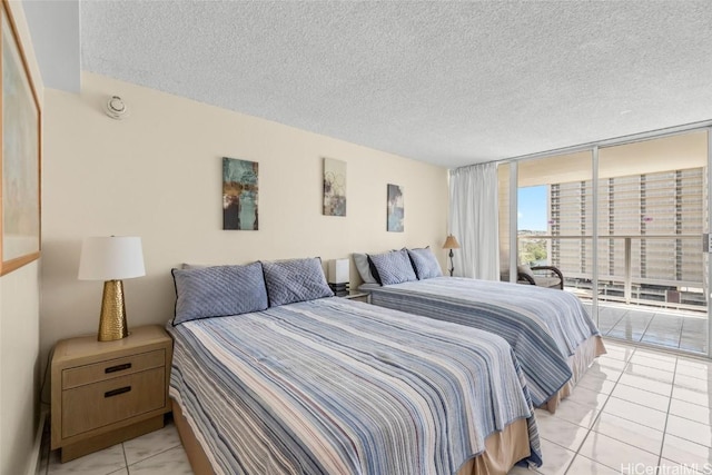 bedroom with expansive windows, access to outside, light tile patterned floors, and a textured ceiling