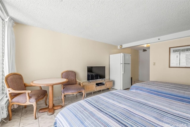 bedroom featuring light tile patterned floors, a textured ceiling, and freestanding refrigerator