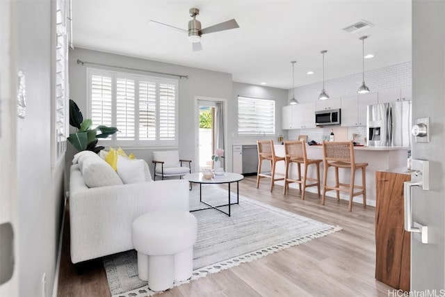 living area with recessed lighting, visible vents, light wood-style flooring, and a ceiling fan