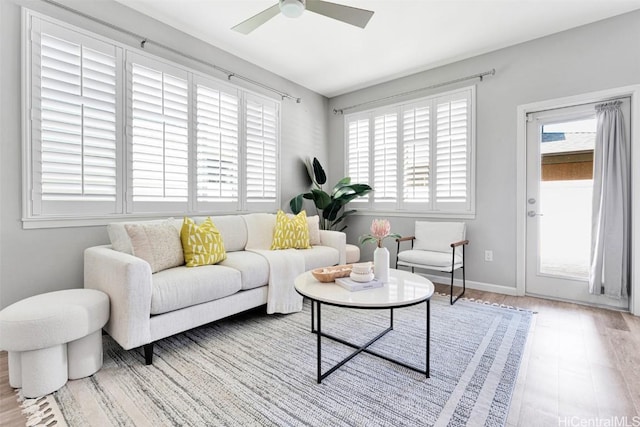 living room with a ceiling fan, wood finished floors, and baseboards