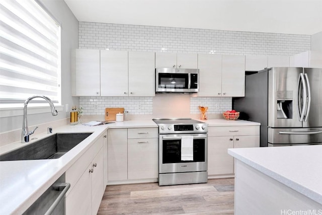 kitchen featuring a sink, light wood-type flooring, backsplash, and stainless steel appliances