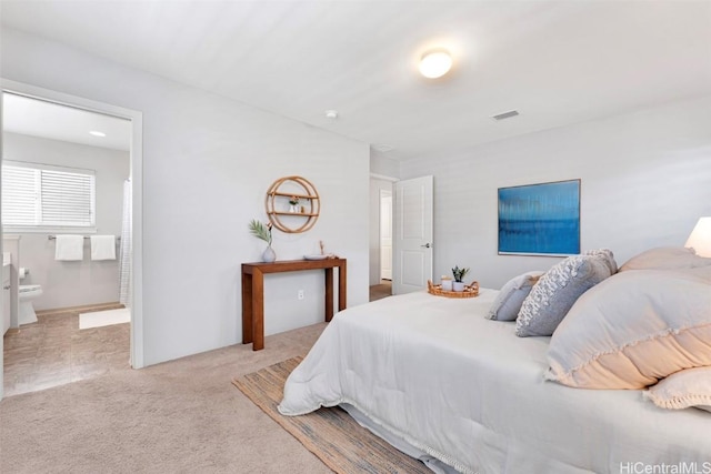 bedroom featuring visible vents, carpet floors, and ensuite bath