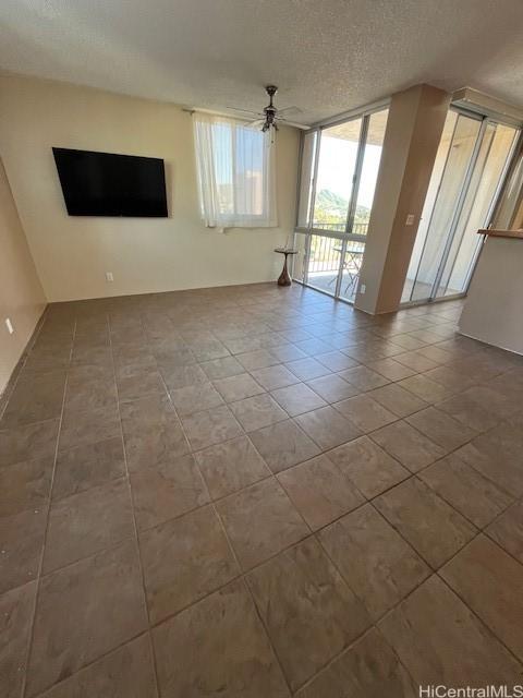 unfurnished living room with a ceiling fan, a textured ceiling, and tile patterned floors