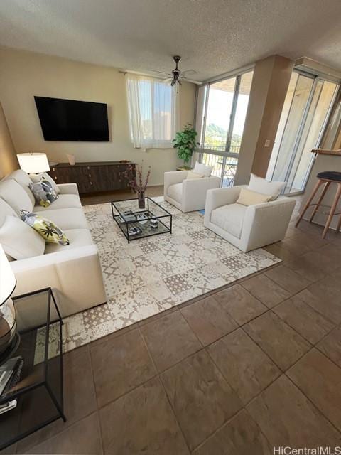 living area with a textured ceiling, ceiling fan, and tile patterned flooring