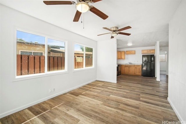 unfurnished living room with a sink, baseboards, and wood finished floors