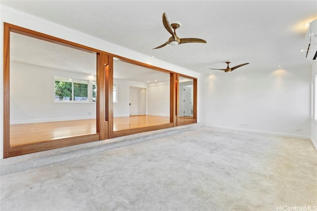 empty room featuring crown molding, carpet floors, a ceiling fan, and baseboards