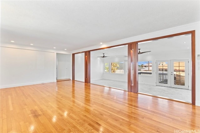 empty room featuring a textured ceiling, french doors, light wood-style flooring, and a ceiling fan