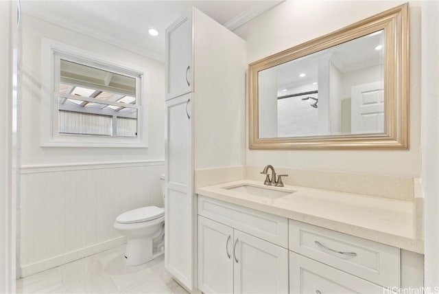 bathroom with a wainscoted wall, vanity, toilet, and crown molding