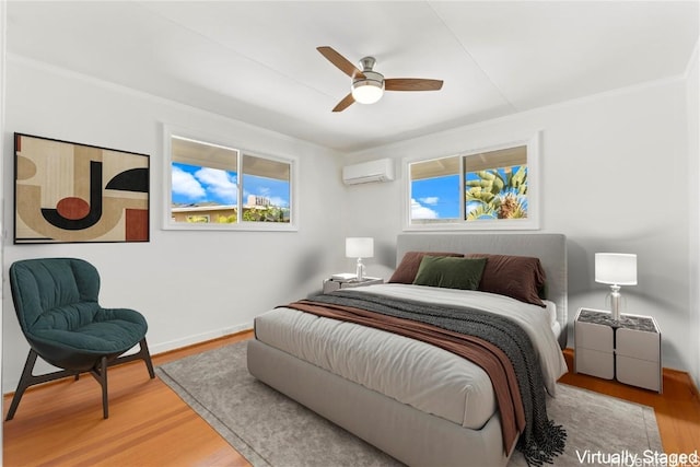 bedroom with ceiling fan, wood finished floors, baseboards, a wall mounted air conditioner, and crown molding