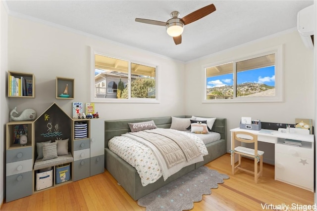 bedroom with crown molding, wood finished floors, and a wall mounted air conditioner