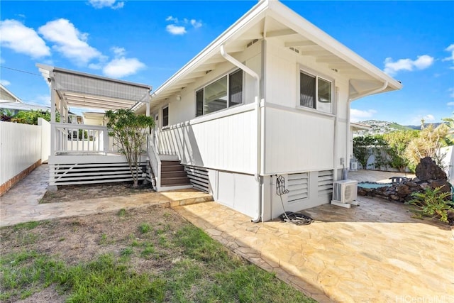 view of side of property featuring a patio area, fence, and a wooden deck