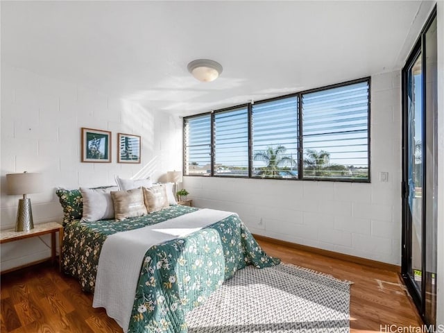 bedroom with concrete block wall and wood finished floors