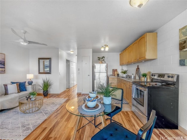 kitchen featuring open floor plan, stainless steel appliances, light countertops, light brown cabinetry, and light wood-style floors