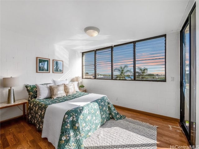 bedroom featuring concrete block wall and wood finished floors