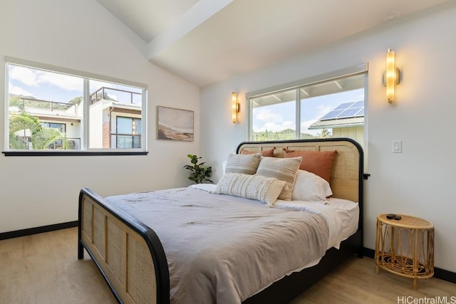 bedroom with vaulted ceiling, baseboards, and wood finished floors