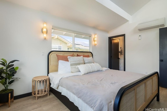 bedroom with light wood finished floors, baseboards, vaulted ceiling, and a wall mounted AC