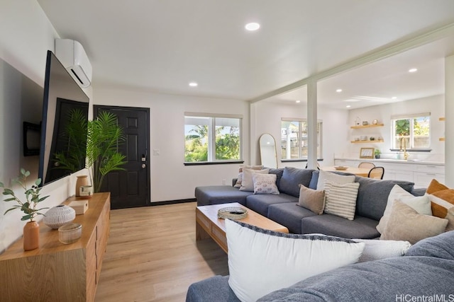 living area featuring a wall mounted air conditioner, light wood-style flooring, and recessed lighting