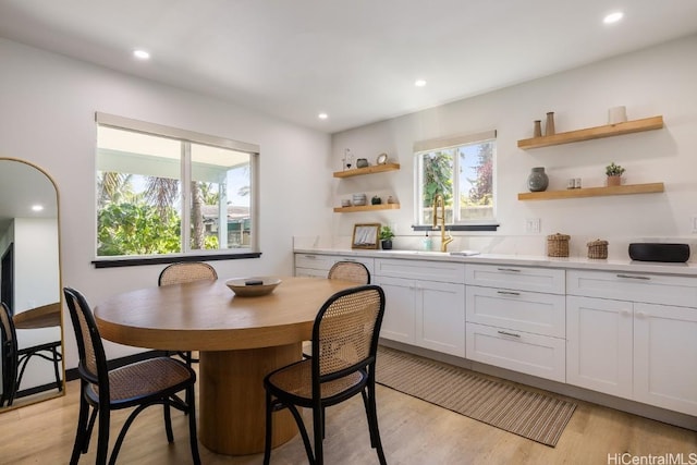 kitchen with open shelves, recessed lighting, light countertops, light wood-style floors, and a sink