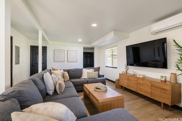 living room featuring light wood-type flooring, electric panel, a wall unit AC, and recessed lighting