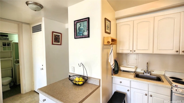 kitchen featuring light countertops, a sink, electric stove, and white cabinets