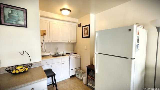 kitchen with white appliances, light tile patterned floors, visible vents, white cabinetry, and a sink