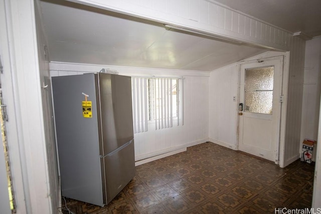 foyer entrance with dark floors and vaulted ceiling