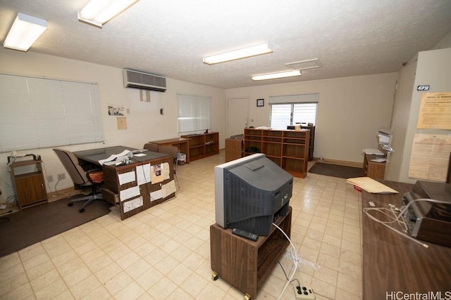 interior space with a textured ceiling, light floors, and a wall mounted AC