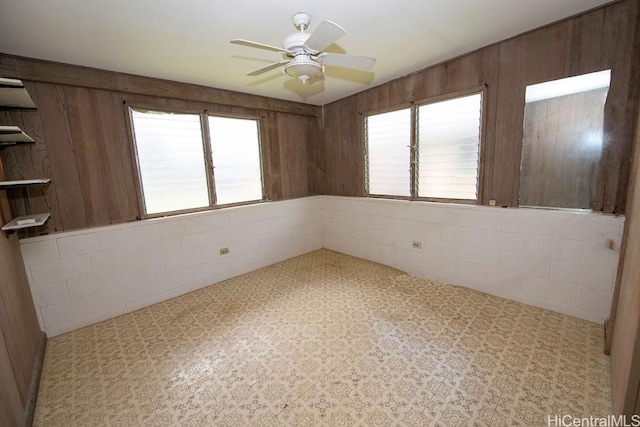 empty room with wood walls and a ceiling fan