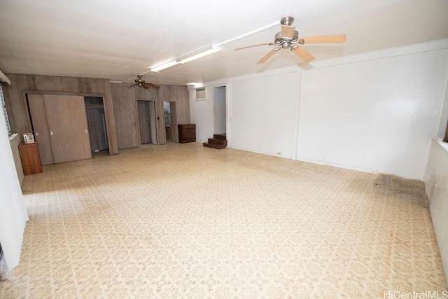 spare room featuring ceiling fan and wooden walls