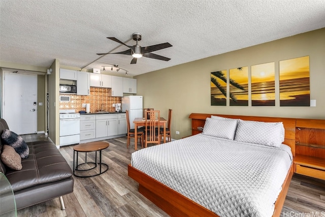 bedroom with a textured ceiling, dark wood-style flooring, and freestanding refrigerator