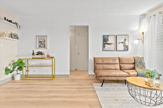 living room featuring a textured ceiling, baseboards, and wood finished floors