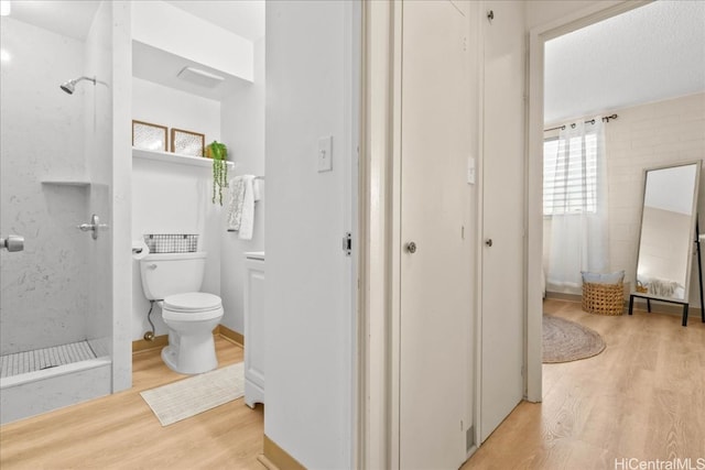 bathroom with wood finished floors, toilet, and walk in shower