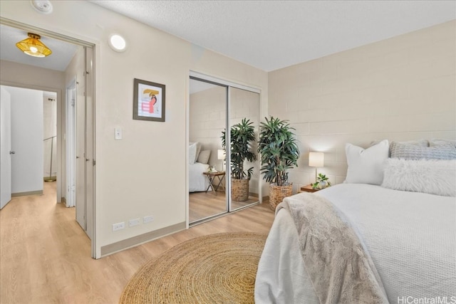 bedroom featuring a closet, light wood-style flooring, and a textured ceiling