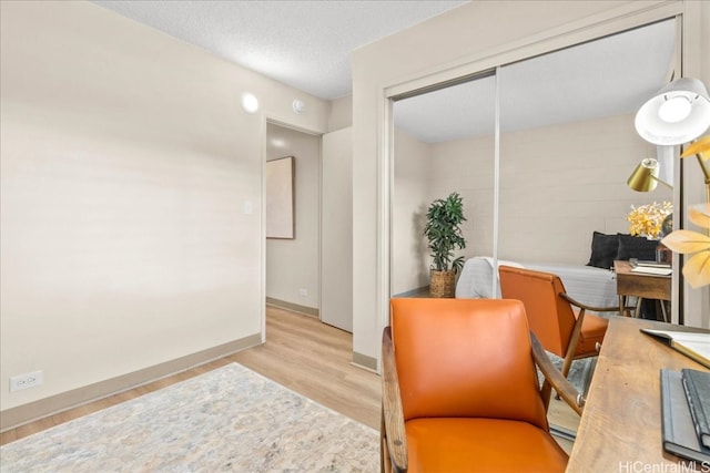 sitting room featuring a textured ceiling, baseboards, and wood finished floors