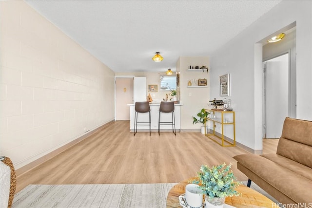 living room featuring concrete block wall, light wood finished floors, and a textured ceiling