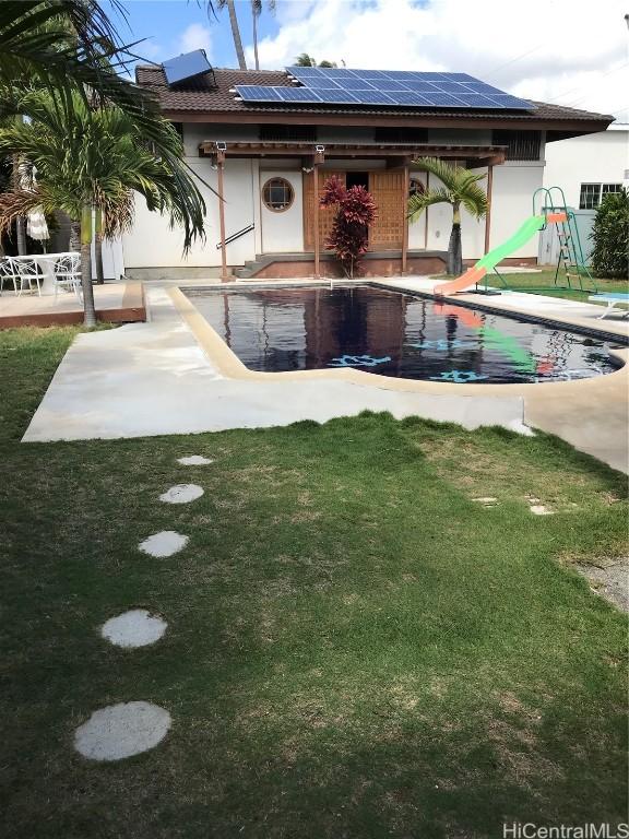 exterior space with a patio, solar panels, an outdoor pool, stucco siding, and a front yard